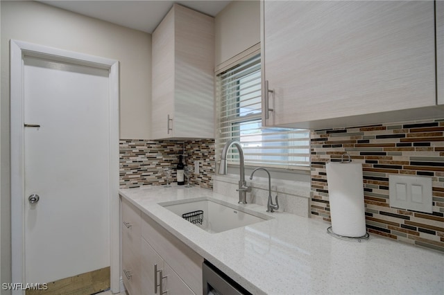 kitchen featuring decorative backsplash, sink, and light stone counters