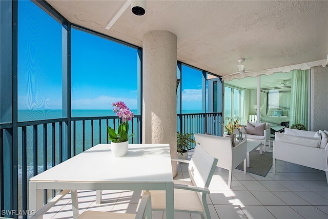 sunroom / solarium with ceiling fan and a water view