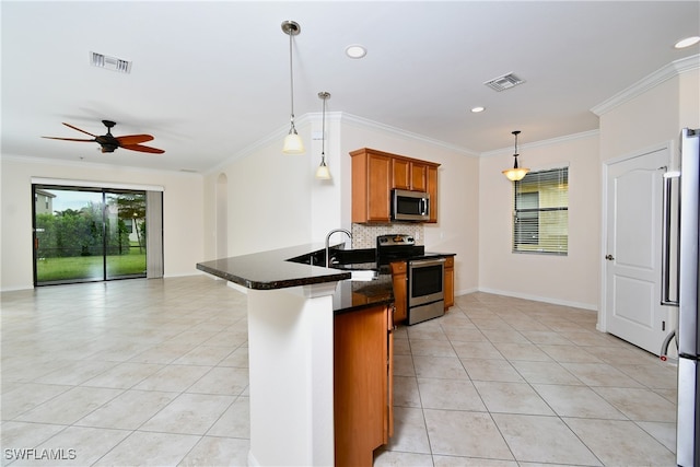 kitchen featuring kitchen peninsula, ornamental molding, stainless steel appliances, sink, and decorative light fixtures