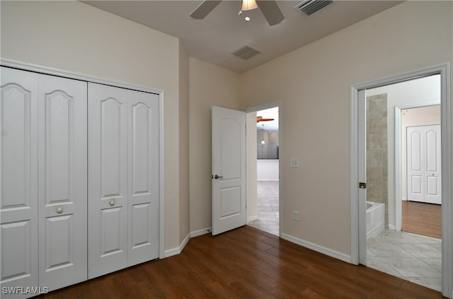 unfurnished bedroom with dark hardwood / wood-style flooring, a closet, ensuite bath, and ceiling fan