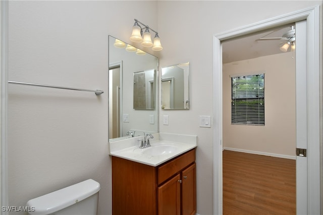 bathroom with hardwood / wood-style flooring, vanity, ceiling fan, and toilet