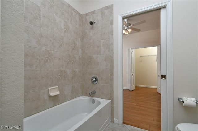 bathroom featuring ceiling fan, wood-type flooring, tiled shower / bath combo, and toilet