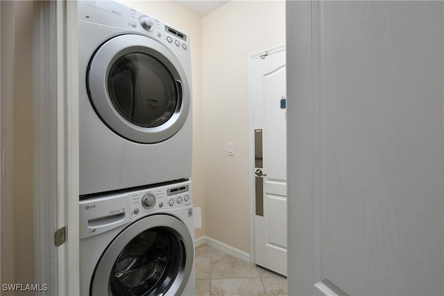 washroom with stacked washer / drying machine and light tile patterned flooring