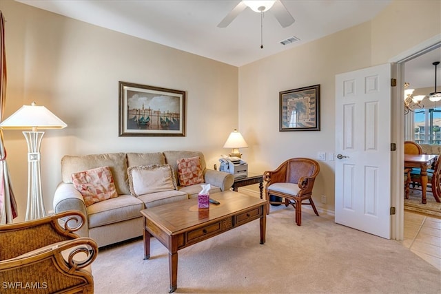 living room featuring light carpet and ceiling fan with notable chandelier