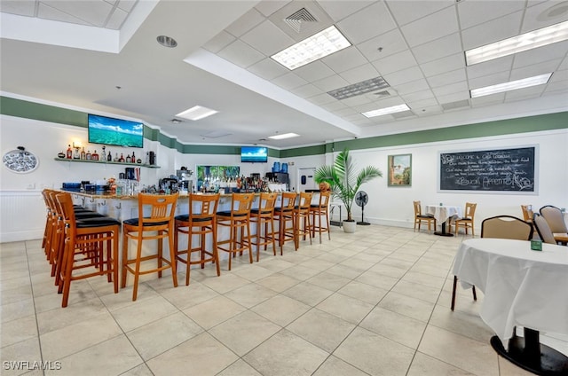 tiled dining room featuring bar area and a paneled ceiling