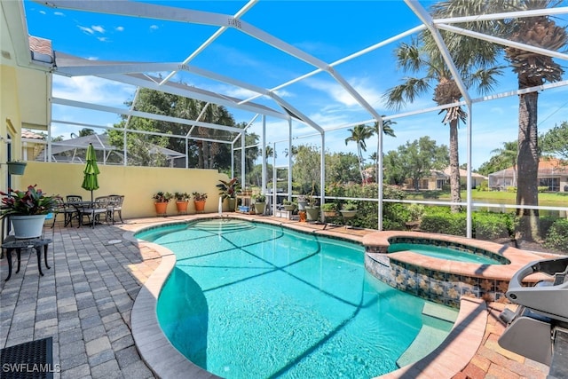 view of pool featuring an in ground hot tub, glass enclosure, and a patio area