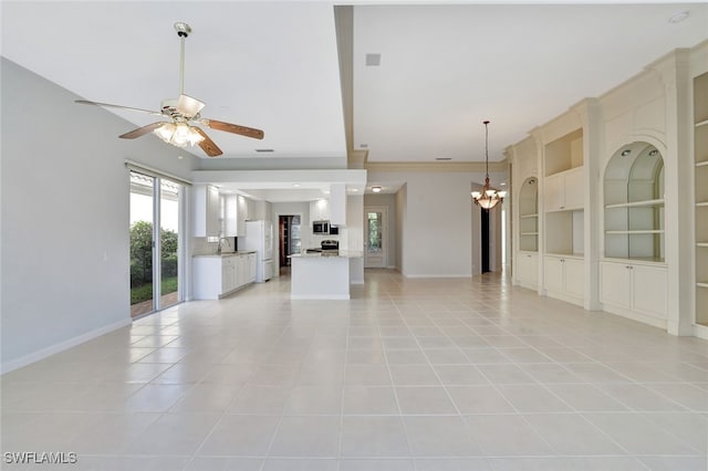 unfurnished living room with built in features, sink, light tile patterned flooring, and ceiling fan with notable chandelier