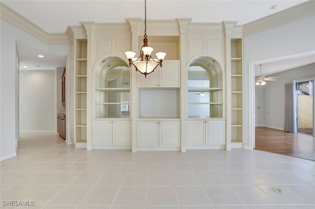 unfurnished dining area featuring built in shelves, ornamental molding, and ceiling fan with notable chandelier