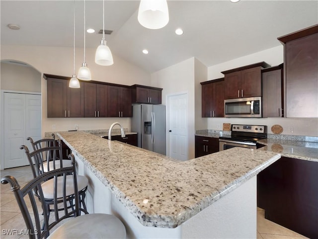 kitchen featuring decorative light fixtures, a center island, stainless steel appliances, and vaulted ceiling