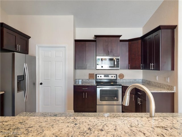 kitchen featuring dark brown cabinetry, light stone countertops, and stainless steel appliances