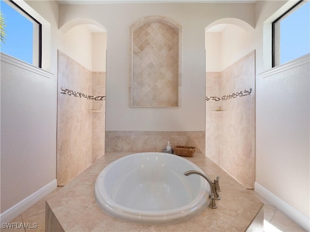 bathroom with tiled bath and tile patterned flooring