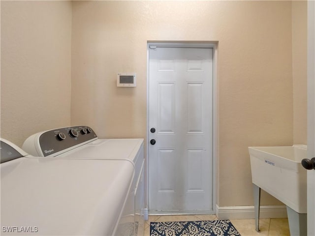 clothes washing area featuring independent washer and dryer, light tile patterned floors, and sink