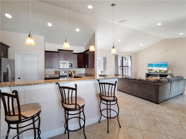 kitchen featuring a kitchen bar, decorative light fixtures, stainless steel appliances, and lofted ceiling