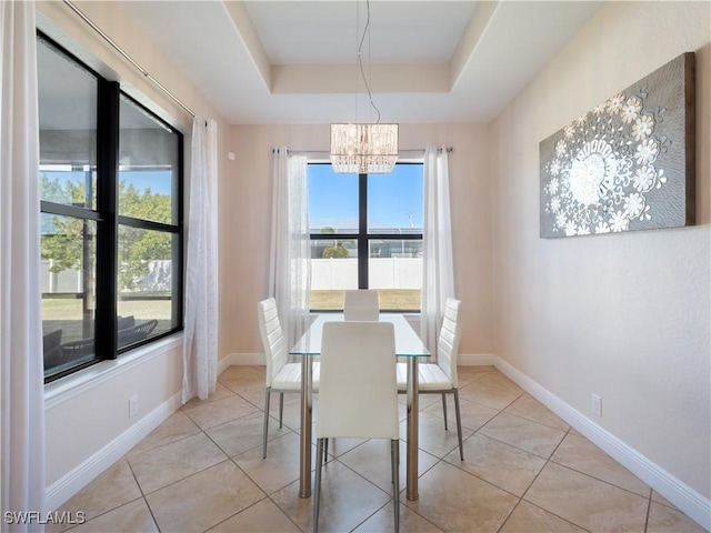 tiled dining room with a chandelier and a raised ceiling