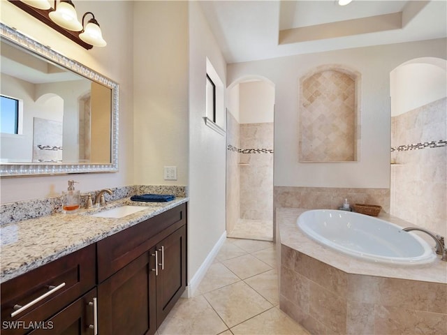 bathroom featuring tile patterned floors, vanity, and a relaxing tiled tub