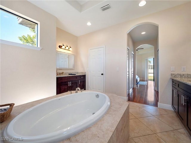 bathroom featuring tile patterned flooring, vanity, and a relaxing tiled tub