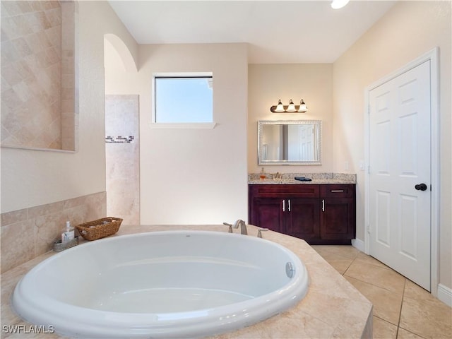 bathroom featuring tile patterned flooring, vanity, and tiled bath