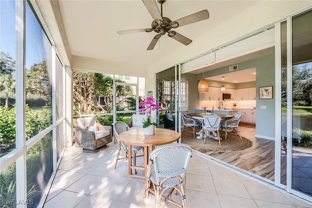 sunroom featuring ceiling fan and sink