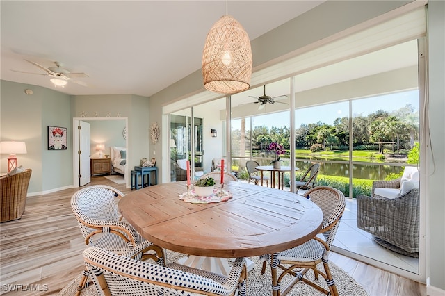 dining room featuring ceiling fan, a water view, and light hardwood / wood-style flooring