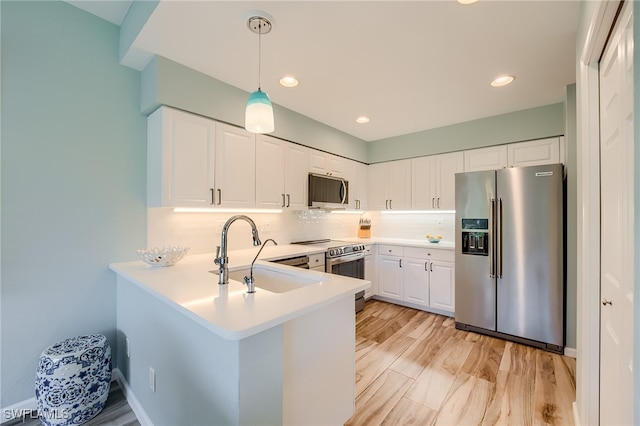 kitchen with backsplash, sink, white cabinetry, kitchen peninsula, and stainless steel appliances