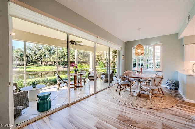 sunroom featuring a water view, a wealth of natural light, and ceiling fan