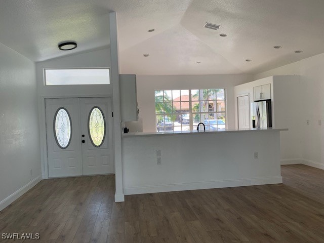 entryway featuring a textured ceiling, dark hardwood / wood-style floors, and lofted ceiling