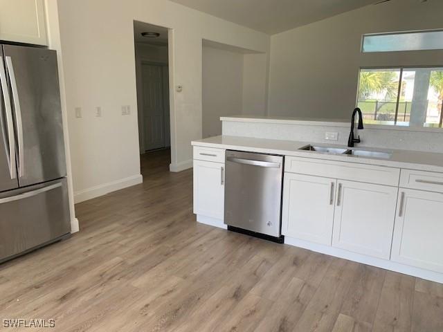 3026 SW 24th Ave, Cape Coral, FL 33914 - kitchen featuring stainless steel appliances, a sink, white cabinets, light wood finished floors, and light countertops