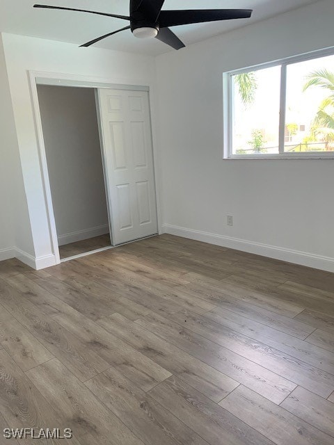 unfurnished bedroom featuring light wood-type flooring, a closet, and ceiling fan