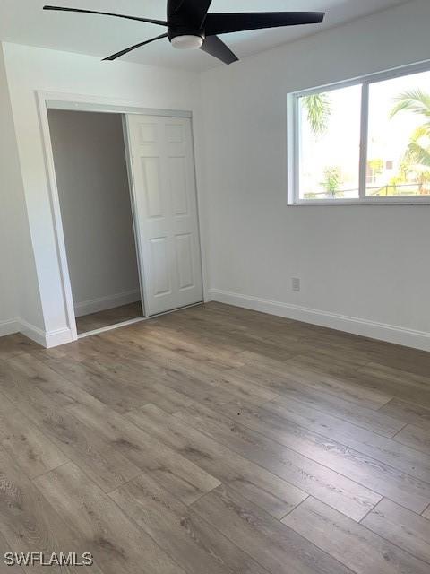 3026 SW 24th Ave, Cape Coral, FL 33914 - unfurnished bedroom with wood finished floors, a closet, and baseboards