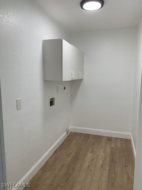 clothes washing area with hookup for an electric dryer, cabinets, light wood-type flooring, and hookup for a washing machine