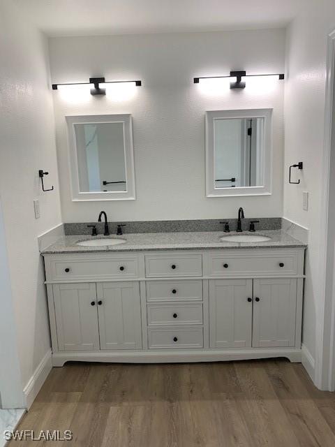 3026 SW 24th Ave, Cape Coral, FL 33914 - full bathroom featuring double vanity, wood finished floors, and baseboards