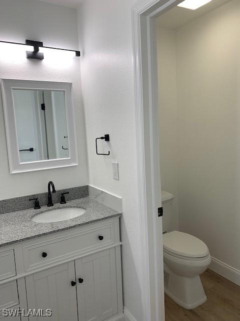 3026 SW 24th Ave, Cape Coral, FL 33914 - bathroom featuring vanity, toilet, baseboards, and wood finished floors