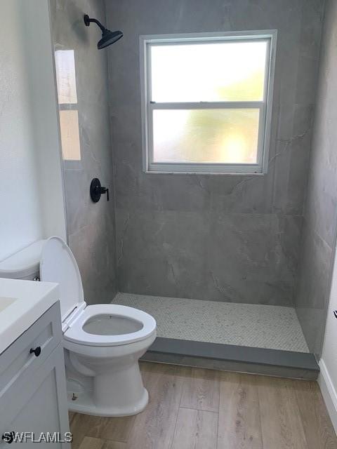 3026 SW 24th Ave, Cape Coral, FL 33914 - full bath with wood finished floors, toilet, vanity, a tile shower, and plenty of natural light