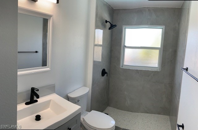 bathroom with vanity, toilet, and a tile shower