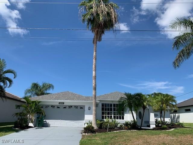 3026 SW 24th Ave, Cape Coral, FL 33914 - single story home with a garage, driveway, stucco siding, and a front lawn