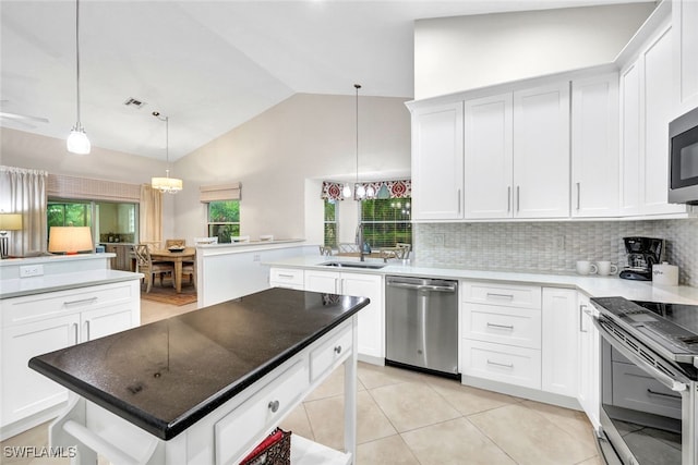 kitchen with stainless steel appliances, sink, a center island, white cabinetry, and hanging light fixtures