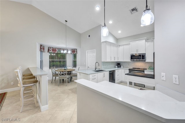 kitchen with pendant lighting, white cabinets, sink, appliances with stainless steel finishes, and kitchen peninsula