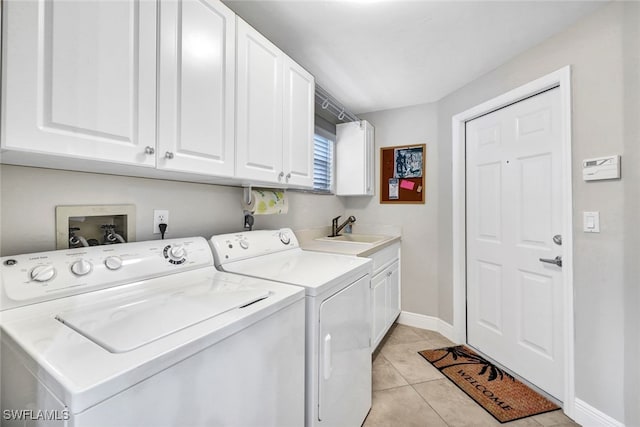 clothes washing area with cabinets, light tile patterned floors, sink, and washing machine and clothes dryer