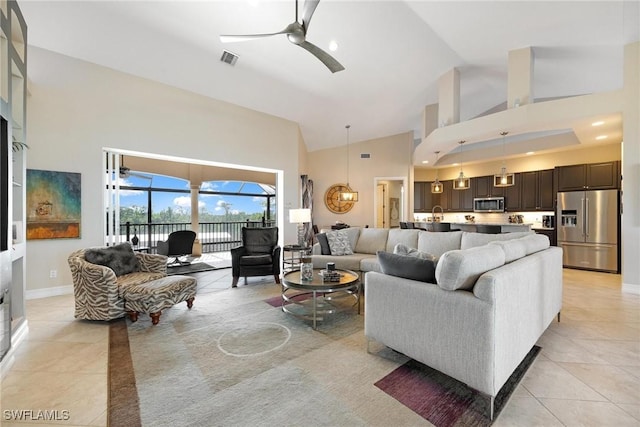 living area featuring light tile patterned floors, visible vents, a ceiling fan, a sunroom, and high vaulted ceiling