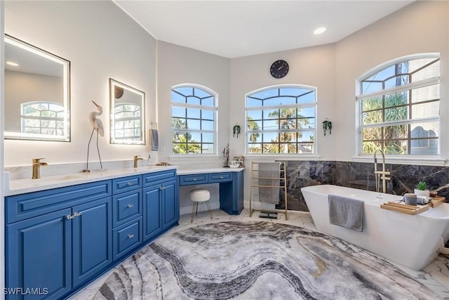 bathroom featuring double vanity, marble finish floor, a freestanding tub, and a sink