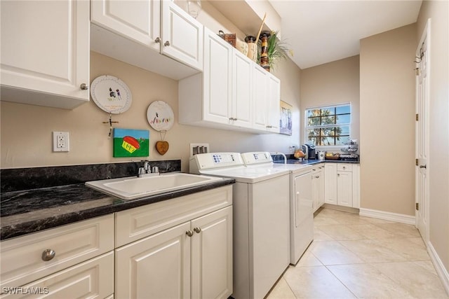 washroom featuring light tile patterned floors, sink, washing machine and clothes dryer, and cabinets