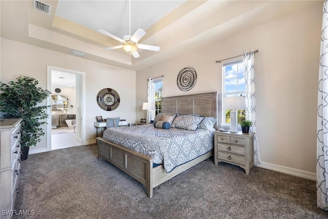 carpeted bedroom with ceiling fan, a tray ceiling, and connected bathroom