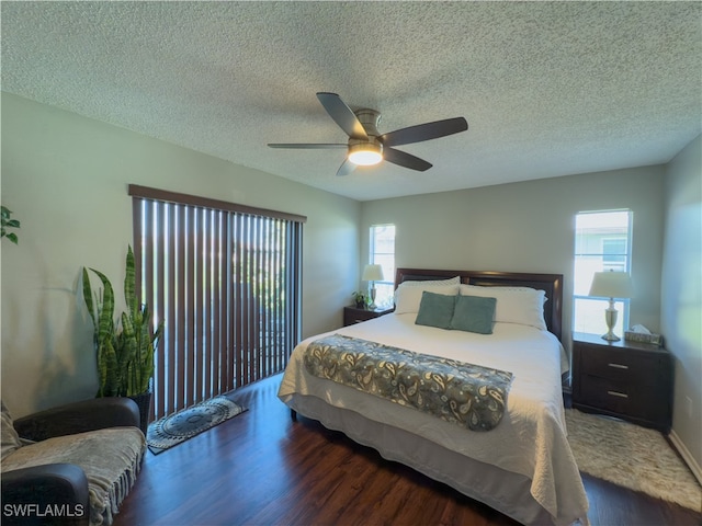 bedroom featuring a textured ceiling, dark hardwood / wood-style floors, multiple windows, and ceiling fan