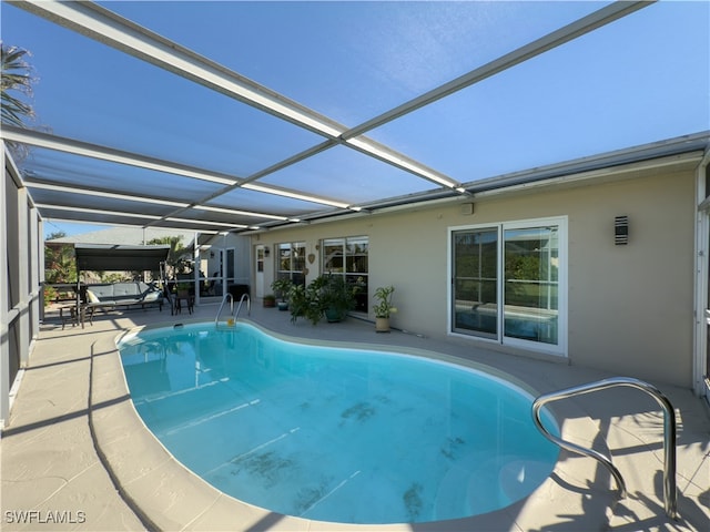 view of swimming pool featuring glass enclosure and a patio area