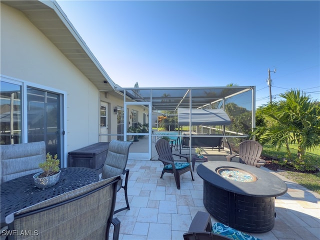 view of patio / terrace with an outdoor fire pit and a lanai