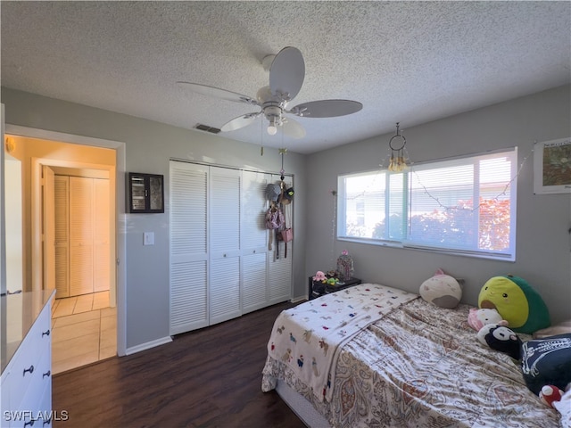 bedroom with ceiling fan, dark hardwood / wood-style flooring, a textured ceiling, and a closet