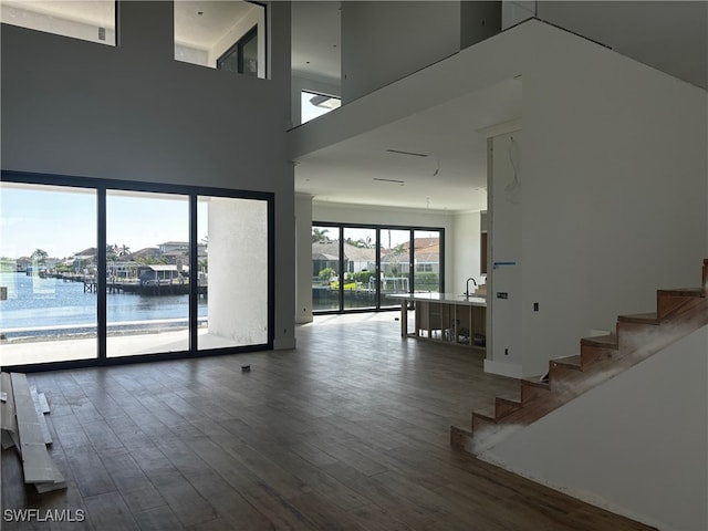 empty room featuring sink, a water view, a high ceiling, and hardwood / wood-style flooring