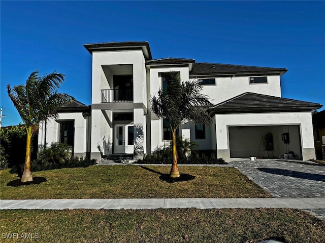 view of front facade featuring stucco siding, a front lawn, decorative driveway, a garage, and a balcony