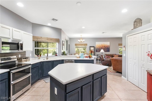 kitchen featuring a center island, light tile patterned floors, stainless steel appliances, and a notable chandelier