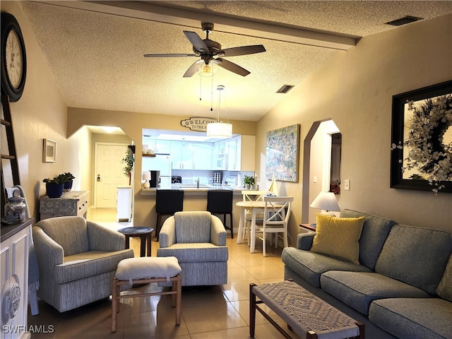 living room featuring lofted ceiling with beams, ceiling fan, light tile patterned floors, and a textured ceiling